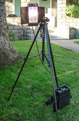Mobile video lighting unit mounted on large tripod for outdoor use. Light is plugged into one of our mobile battery power packs.